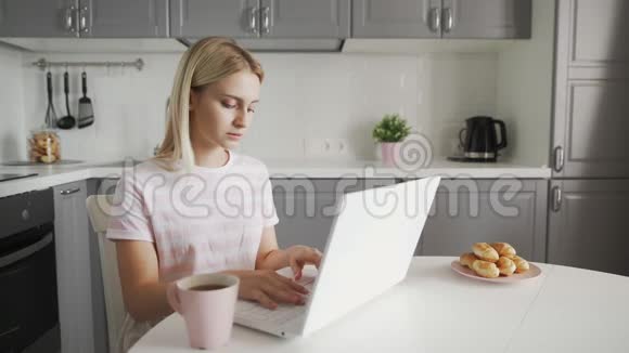 体贴的女人在厨房喝咖啡用笔记本电脑做笔记本的女商人视频的预览图
