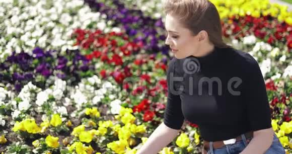 女性穿着休闲服装坐在花坛边的侧景视频的预览图