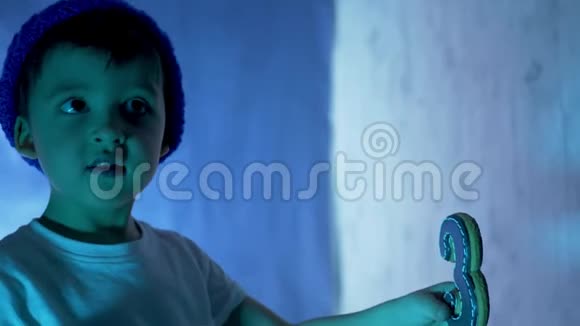 穿着蓝色帽子和白色t恤的小男孩吃一个喜庆的黑色蛋糕视频的预览图