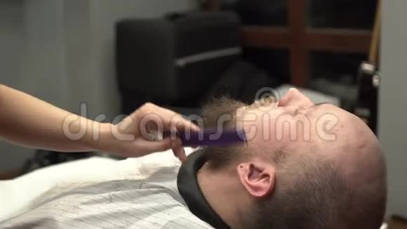 女人手用紫色梳子和黑色电动剃须刀修剪胡须男人的胡须视频的预览图