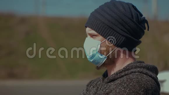 一张站在户外戴着医疗面罩以抵御流感或冠状病毒的人的肖像转过头来看着视频的预览图