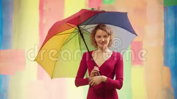 漂亮的女模特用手在彩虹背景上玩彩虹戴彩虹生日帽的滑稽女孩视频的预览图