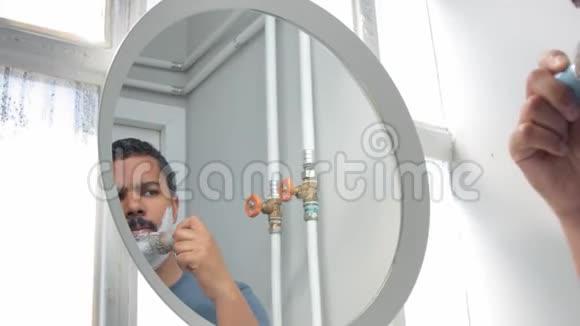 在镜子后面的人在他早晨的面部护理过程中视频的预览图