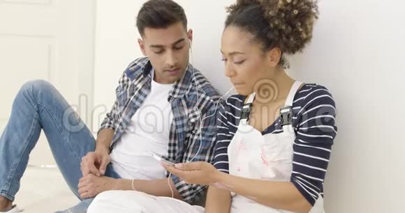 年轻的黑人夫妇坐着听音乐视频的预览图
