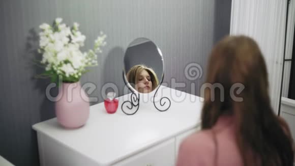 漂亮的年轻女子正在用吹风机照镜子视频的预览图