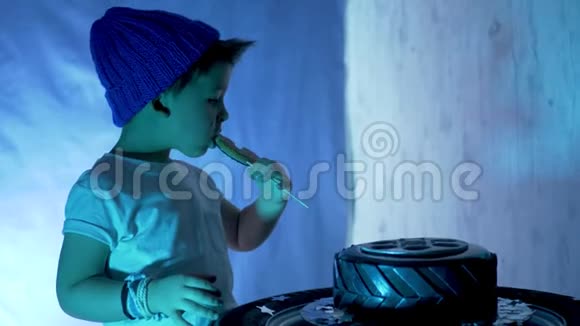 穿着蓝色帽子和白色t恤的小男孩吃一个喜庆的黑色蛋糕视频的预览图