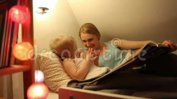 妈妈和女儿睡觉前在床上一起玩视频的预览图