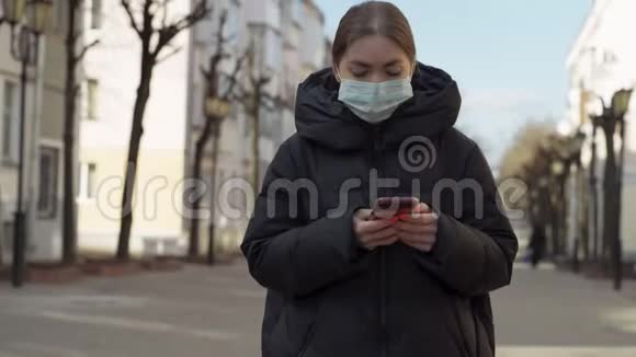 在空荡荡的欧洲街道上使用智能手机戴防护医疗面具的妇女的肖像健康与安全N1H1视频的预览图