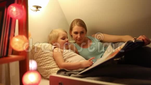 母亲和女儿睡觉前在床上一起读童话视频的预览图