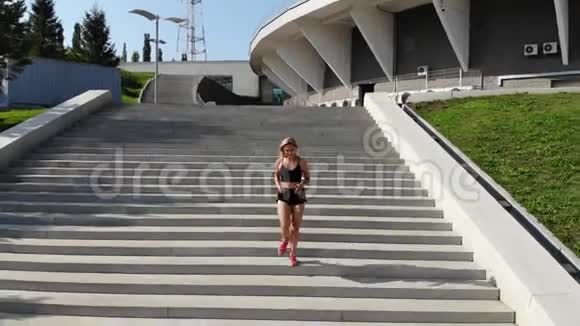 在阳光明媚的早晨年轻迷人的运动女性在城市沥青上跑步和锻炼的最高景观视频的预览图
