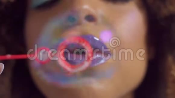 混合种族妇女与紫罗兰光泽的唇膏在吹泡泡风机向相机视频的预览图