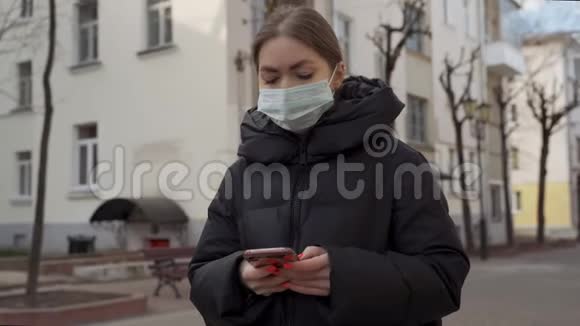 在空荡荡的欧洲街道上使用智能手机戴防护医疗面具的妇女的肖像健康与安全N1H1视频的预览图