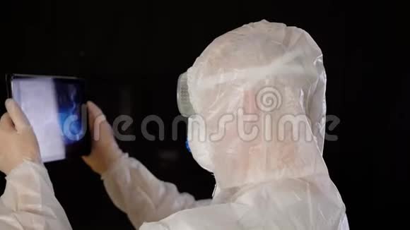 病毒学家穿着防护服戴着口罩手持数字平板进行研究生物工程师寻找DNA结果平板电脑视频的预览图