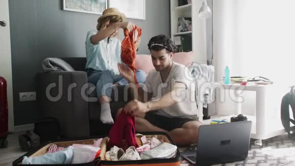 沙发上戴帽子的女孩和一个拿着笔记本电脑在旅行中整理东西的男人视频的预览图