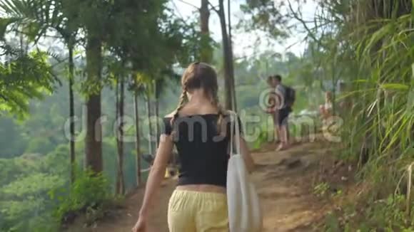 苗条的女孩沿着被树木包围的高地小径散步视频的预览图