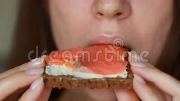 吃红鱼和黄油三明治的贴身女人女孩嘴咬一个鲑鱼三明治从全麦面包视频的预览图
