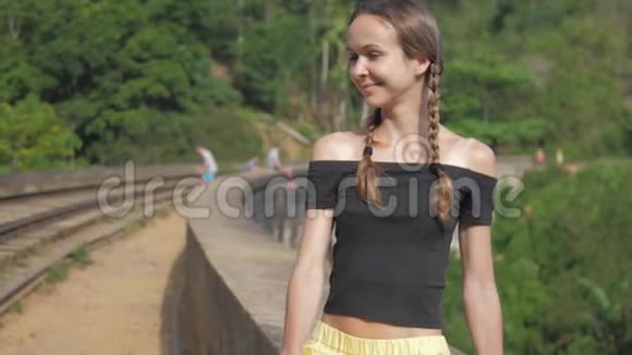 女孩坐在桥栏上对热带自然微笑视频的预览图