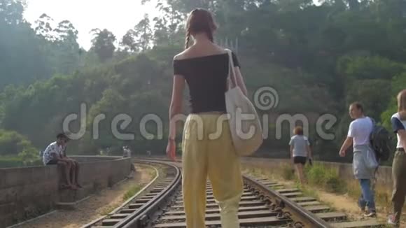 女游客在丛林之间的旧铁路上散步视频的预览图