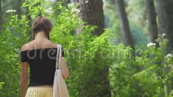 布鲁内特在开阔的肩膀上沿着绿色的草地散步视频的预览图