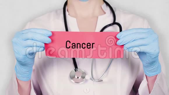 特写双手戴着蓝色医用手套手持撕红纸卡上面刻着癌症穿着衣服的医生视频的预览图