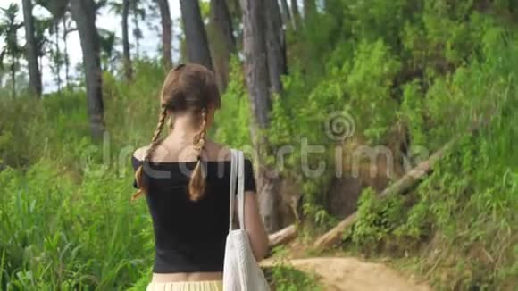 苗条的女孩沿着被树木包围的高地小径散步视频的预览图