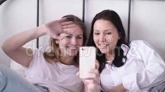 两位年轻女性在电话上自画像女性展示积极的面孔情绪笑着挥舞双手享受乐趣视频的预览图