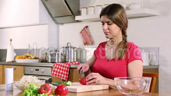 年轻的成年女人切番茄做蔬菜沙拉视频的预览图