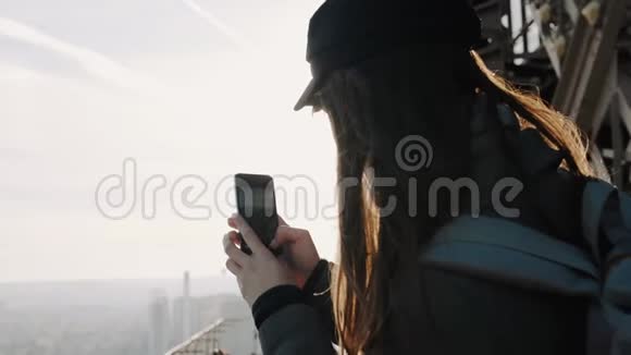 快乐年轻的旅行博主女士从埃菲尔铁塔顶部拍摄智能手机照片在度假时慢动作视频的预览图