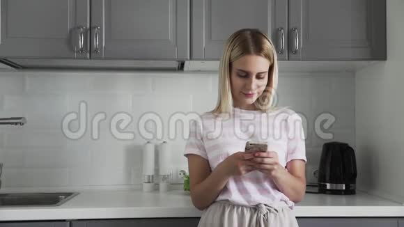 早上在厨房检查电话里关小女孩女人用手机和朋友聊天女孩视频的预览图