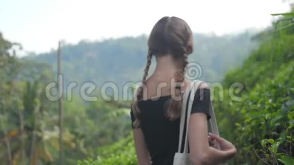 女士沿着绿茶种植园之间的高地小径散步视频的预览图