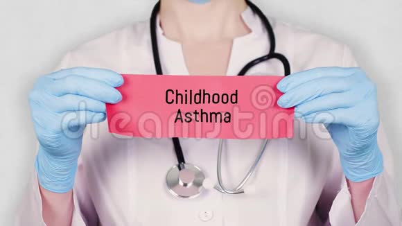 特写双手戴蓝色医用手套手持撕红纸牌上刻有童年哮喘字样医生视频的预览图