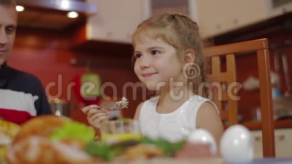 快乐的女孩和她的家人在同一张桌子上吃饭在家庆祝节日全家围桌吃饭视频的预览图