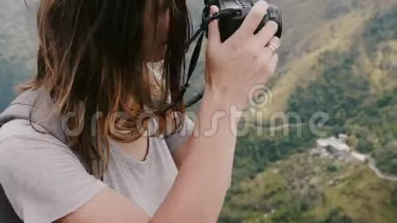为斯里兰卡史诗般的山景拍摄照片的年轻记者女士带着背包和飞扬的头发视频的预览图