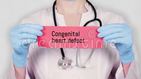 特写双手戴蓝色医用手套手持撕红纸卡上面刻有先天性心脏缺损医生视频的预览图