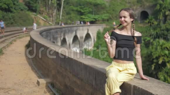 穿着黑色上衣的女孩在老桥上摆姿势微笑着面对森林视频的预览图