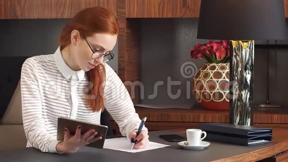 时髦的红头发女孩在家庭办公室工作视频的预览图