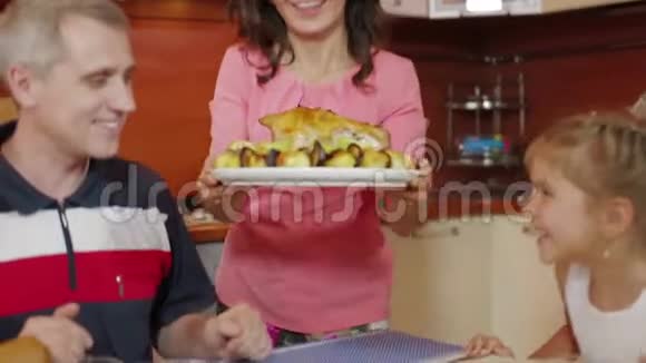 年轻女子在餐桌上放了一盘烤鸡在厨房里庆祝生日幸福家庭视频的预览图