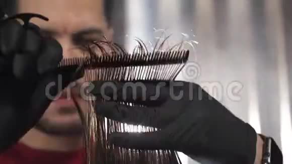 特写理发师用剪刀剪客户头发的镜头理发师的梳子给顾客梳头剪下头发视频的预览图