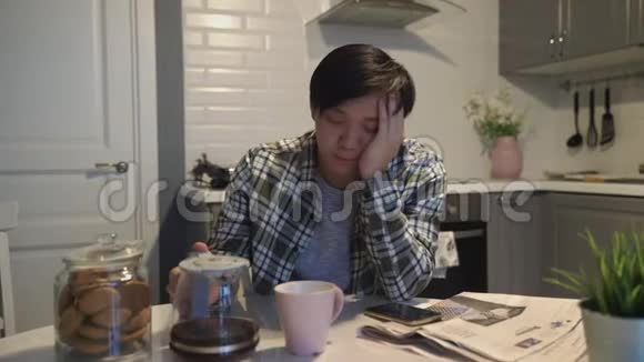 一个睡意朦胧的男人在餐桌上吃早餐视频的预览图