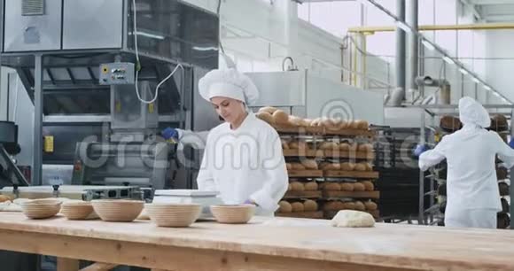 有魅力的女面包师穿着白色制服准备面团烘焙面包其他工人集中背景视频的预览图