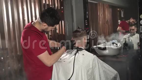理发师用电动剃须刀把头发剃在后脑勺上穿红色t恤的理发师在理发店理发视频的预览图