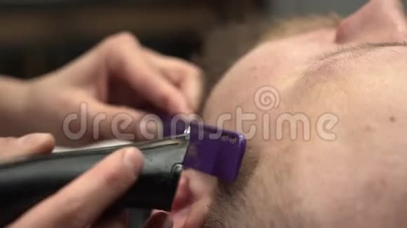 特写女性手的镜头用紫色梳子和黑色电动剃须刀修剪胡须男人的胡须视频的预览图