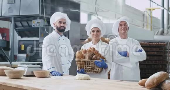 两代面包师在一个大面包店里两个男人和女人直视着摄像机微笑着站在旁边视频的预览图