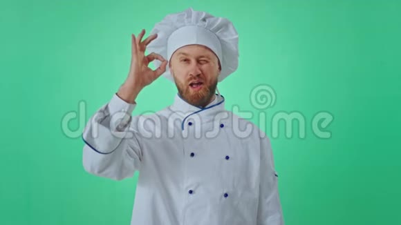 在一个绿色的工作室里一个漂亮的面包师非常有魅力在镜头前摆着姿势他用手做手势视频的预览图