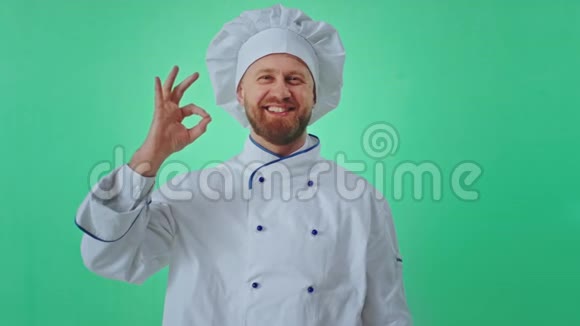 有魅力的有趣的面包师男人穿着绿色工作室的制服显示出一个大的喜欢和好的手势视频的预览图