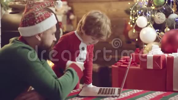 父亲和儿子在圣诞节玩得很开心可爱的小儿子和爸爸带着笔记本圣诞家庭快乐的父亲视频的预览图