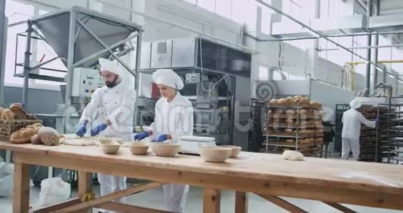 大面包店行业两个面包师集中成型面团用于烘焙面包背景大面包店视频的预览图