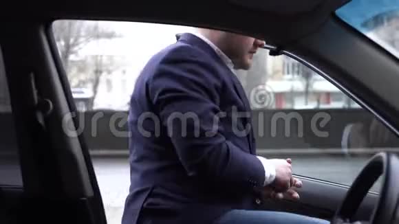 穿着蓝色夹克的商人坐在他的SUV和白色衬衫上的解开纽扣这个人对工作日很累视频的预览图