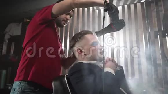 在理发店一个男人的发型是吹风机理发店的客户用吹风机烘干视频的预览图