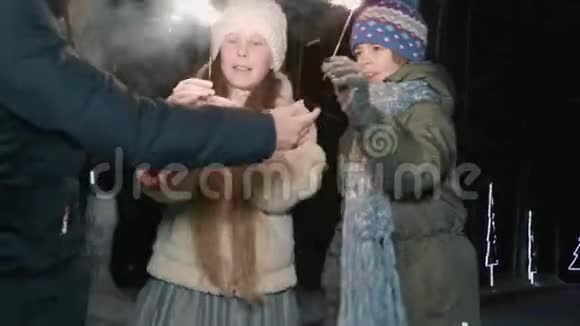 快乐的男孩和女孩青少年在黑暗的公园里冬天拿着火花走快乐的女孩和男孩与孟加拉灯视频的预览图